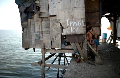 Un grupo de niños descansan en una chabola construida en el rompeolas de la bahía de Manila (Filipinas).