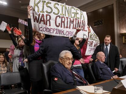 Un grupo de manifestantes con pancartas que acusan a Henry A. Kissinger, en el centro, de ser un criminal de guerra, interrumpen una sesión en el Capitolio, en enero de 2015.