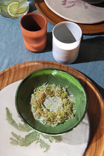 <p><b>ACHICORIA CON CASTAÑAS Y AJOBLANCO DE PLANCTON</b></p> <p><b>Ingredientes. </b>Para cuatro personas: 500 gramos de achicoria, 200 gramos de castañas peladas, asadas y troceadas. Para la sopa de almendras con plancton: 1 litro de leche de almendras, 450 gramos de almendra marcona frita, 2 dientes de ajo, 5 gramos de plancton, 25 gramos de agua, 15 gramos de vinagre de arroz blanco japonés, 10 gramos de jang (esencia de soja), 30 gramos de miga de pan blanco.</p> <p><b>Elaboración. </b> 1. En un bol introducir las almendras y la leche, añadir el ajo y la miga de pan. Dejar reposar esta mezcla durante al menos cinco horas. 2. Mientras se macera la mezcla, rehidratar el plancton en el agua. 3. Una vez tengamos ambas elaboraciones, triturar por un lado la mezcla de leche, ajos, almendras y miga de pan en un robot de cocina a máxima velocidad durante cuatro minutos. 4. Transcurrido el tiempo, pasar por un chino fino sin apretar demasiado para evitar que caigan posos de la almendra. 5. Añadir al ajoblanco el plancton rehidratado, el vinagre de arroz blanco y el jang. Reservar hasta su utilización en un recipiente de plástico hermético. 6. Limpiar bien la achicoria para despojarla de los restos de tierra que pueda tener. Quitar las capas exteriores y desecharlas, ya que son demasiado amargas. 7. Cortar el tallo de la achicoria en cubos de medio centímetro y la parte de las hojas en juliana muy fina. Reservar en agua y hielo. 8. Escurrir del agua y colocar en un plato en forma de corona. Espolvorear por encima las castañas. 9. Verter el ajoblanco en el centro de la corona en el último momento.</p> <p>Los bajoplatos, de Mahe Homeware, son de madera de teca con certificado FSC (35 euros la unidad). El mantel, también de Mahe Homeware, es de lino 100% lavado a la piedra (70 euros). El plato y el cuenco de gres han sido diseñados por la ceramista María Gómez de Agüero (25 euros y 12 euros la unidad). Los vasos de gres blanco son de Laon Pottery (25 euros la unidad), y los de cerámica sin esmaltar, de Alfarería Padilla.</p>