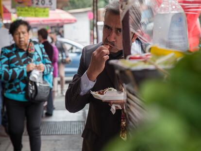 Un hombre come tacos en un puesto callejero en Ciudad de México, en 2021.