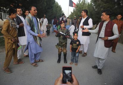 Un hombre toma una foto de su hijo con un niño afgano vestido de soldado durante las celebraciones del Día de la Independencia en Kabul, Afganistán. El presidente de Afganistán se compromete a eliminar todos los refugios seguros del grupo Estado Islámico a medida que el país marca un tenue centésimo Día de la Independencia después de un horrible ataque de boda reclamado por el afiliado local de ISIS.