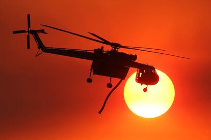 Un helicóptero pasa frente al sol al atardecer, cerca de Hemet, California.