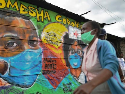 Una mujer con mascarilla pasa por delante de una pintura mural en la que se lee 'Komesha Corona' ("Acabemos con el corona", en suajili) en el barrio de Mathare de la capital de Kenia, 29 de abril de 2020.