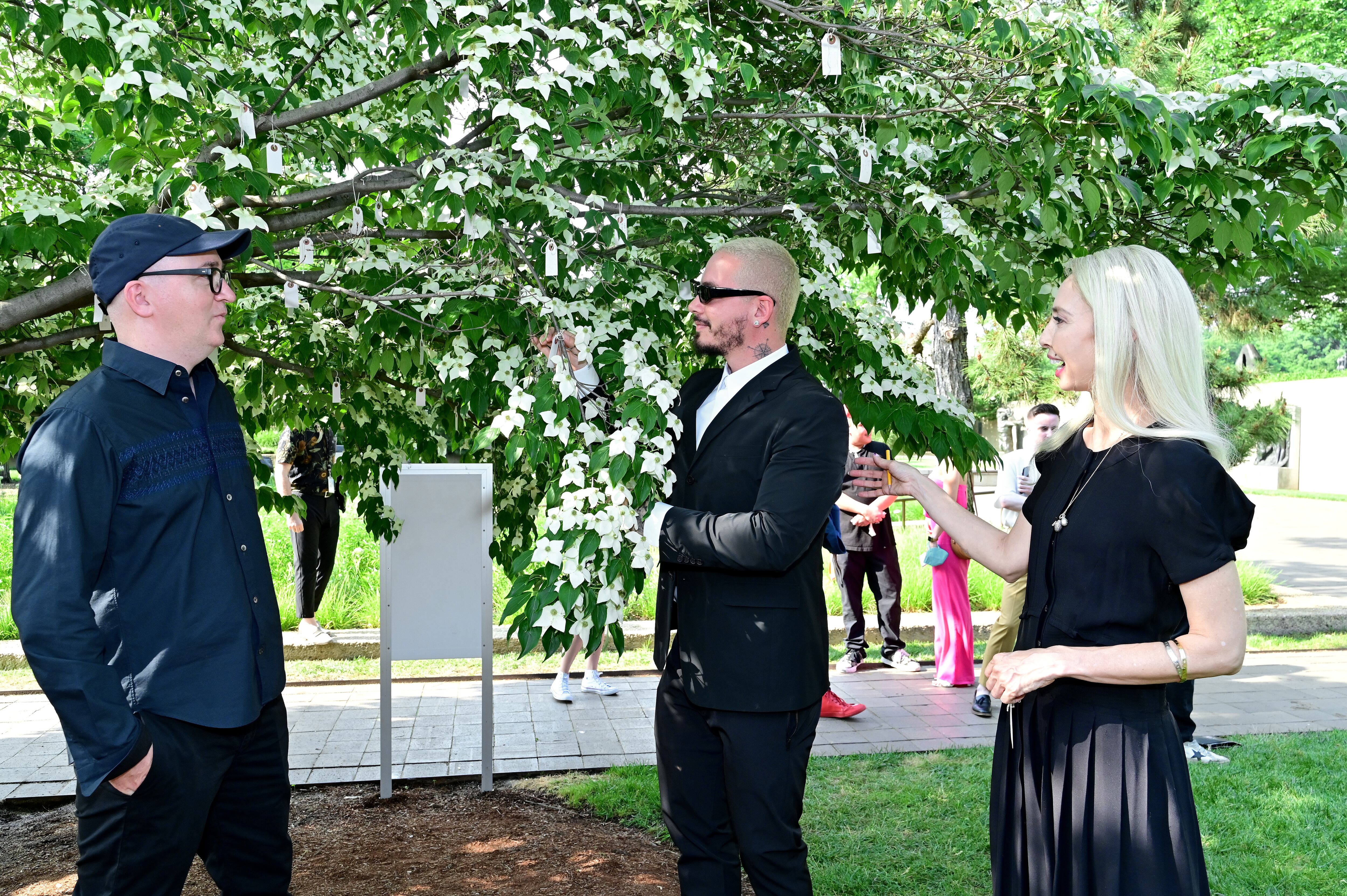 Desde la izquierda, el grafter KAWS, el músico J Balvin y Melissa Chiu, directora del Hirshhorn, ante el árbol de los deseos de Yoko Ono en el jardín del museo, el 20 de mayo de 2022.