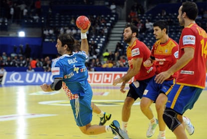 Balic suelta el brazo ante la mirada de tres jugadores de la selección española.