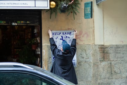 Uno de los propietarios de 'Desperate Literature' pega un cartel en la fachada del local de la calle Campomanes 13 anunciando la mudanza.