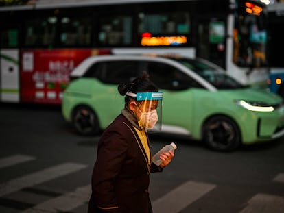 Una mujer con mascarilla y pantalla protectora pasea por el barrio de Huangpu en Shanghái (China).