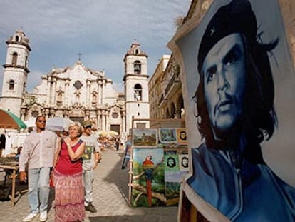 Unos turistas pasan por delante de un cartel de Ernesto <i>Che</i> Guevara en La Habana.