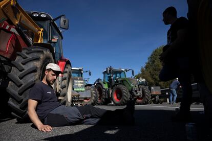 Un agricultor descansa apoyado en su tractor en la AP-7, donde alrededor de 200 payeses siguen instalados tras 24 horas del corte iniciado el martes.