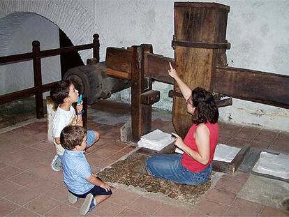 La guía del museo de Capellades, Luisa Huerta, plancha papel para mostrar el funcionamiento del mazo satinador.