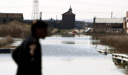 Un hombre camina junto a una carretera inundada tras la crecida del Ebro en Aragón.