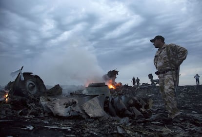 Restos, aún en llamas, del avión de Malaysia Airlines derribado en Grabovo, al este de Ucrania. Era una zona sometida a fuertes combates. En la imagen, varias personas caminan entre los escombros.