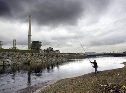 Un pescador junto a la incineradora del Besòs, en Barcelona. Los ecologistas aseguran que las plantas emiten sustancias tóxicas.