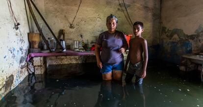 A woman and her son pose inside their flooded house in San Felix, Bolivar state, Venezuela, on August 10, 2018. - The Orinoco river floods have damage houses, crops and generate a potential outbreak to diseases for which medicines are lacking. The floods affect eight states, according to the government. (Photo by William R. Urdaneta / AFP)