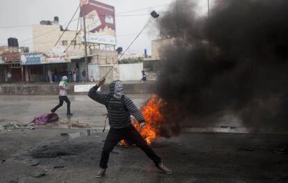 Un palestino utiliza una honda durante los enfrentamientos con las tropas israelíes en el puesto de control de Qalandia, cerca de la ciudad cisjordana de Ramala.