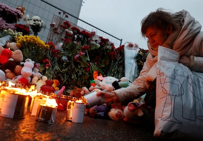 Una mujer coloca una vela en un altar  improvisado en Moscú, este sábado. 