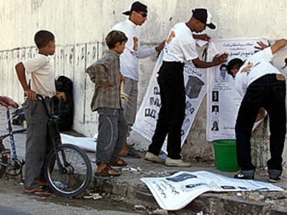 Varios jóvenes colocan carteles con propaganda electoral en una calle de Casablanca. ESCENA