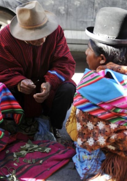 Un puñado de hojas de coca entre dos ciudadanos bolivianos.