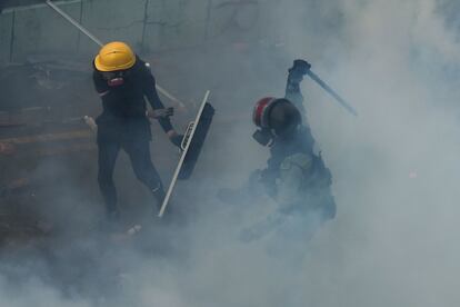 Um manifestante que tenta escapar do cerco da polícia é atingido por um policial do choque. Depois que um policial foi ferido no domingo por uma flecha lançada por um manifestante, as forças de segurança alertaram que eles recorrerão a "balas reais" pela primeira vez desde o início dos protestos em junho passado, que nos últimos dias atingiram níveis de violência sem precedentes.