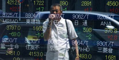 Un hombre mira un monitor instalado en plena calle de Tokyo. 