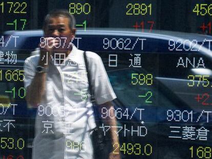 Un hombre mira un monitor instalado en plena calle de Tokyo. 