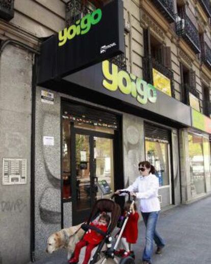 Una mujer y su hijo pasan ante una tienda de Yoigo, en Madrid.