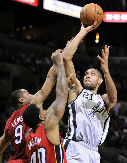 Duncan, de los Spurs, lanza a canasta pese a la oposición de Haslem y Lewis, de los Heat.