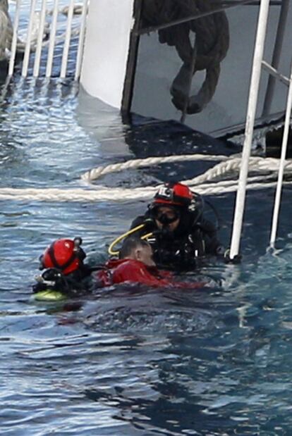 Dos buzos recuperan un cadáver junto al barco.