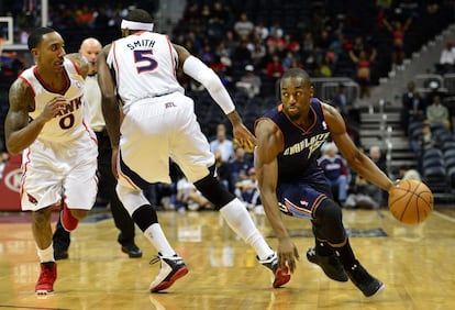 Kemba Walker, de Charlotte Bobcats, se escapa de la marca de Josh Smith y de Jeff Teague, de Atlanta Hawks