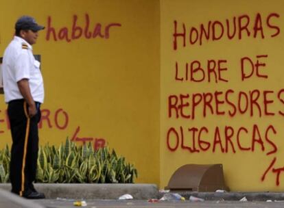 Un policía hondureño observa una pintada en la Casa Presidencial en Tegucigalpa.