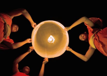 Tres monjes preparan un globo de papel durante el Loi Krathong.