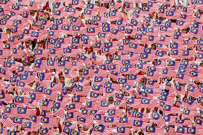 Cientos de niños malasios ondean la bandera nacional durante un simulacro de la celebración del Día de la Independencia, en Putrajaya (Malasia).