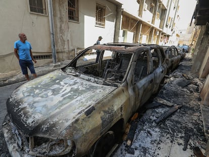 Vecinos observan los vehículos calcinados tras los enfrentamientos armados registrados en Trípoli el pasado 28 de agosto.