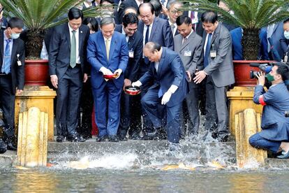 El Primer Ministro japonés Yoshihide Suga y su homólogo vietnamita Nguyen Xuan Phuc alimentan a los peces en un estanque del recinto del Palacio Presidencial en Hanoi (Vietnam).