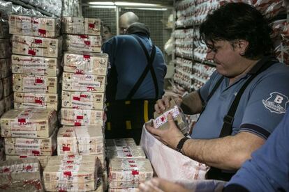 Empleados embolsan los patacones antes de sus destrucción.