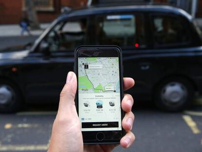 Una mujer sostiene un tel&eacute;fono con la App de Uber en Londres