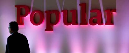 Un hombre permanece cerca del logotipo de Banco Popular