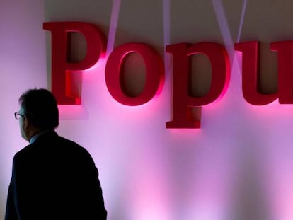 Un hombre permanece cerca del logotipo de Banco Popular