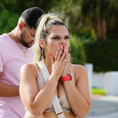 A woman reacts as she looks at a partially collapsed building in Surfside north of Miami Beach, on June 24, 2021. - A high-rise oceanfront apartment block near Miami Beach partially collapsed early JUNE 24, 2021, killing at least one person and leaving 99 unaccounted for, with fears the toll may rise much higher as rescuers comb through the rubble. (Photo by Eva Marie UZCATEGUI / AFP)