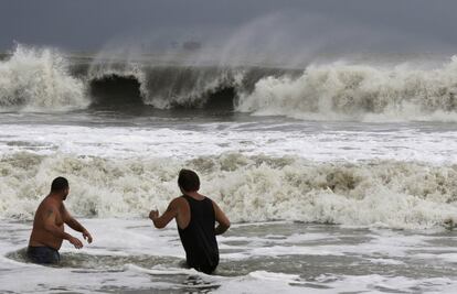 John Cunningham, izquierda, y Hunter Shows, a la derecha, observan cómo se estrellan las olas de la tormenta tropical Gordon en Dauphin Island, Alabama. 
