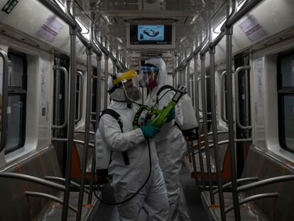 Trabajadores de la cuadrilla de desinfección trabajan en uno vagón de la linea 1 
