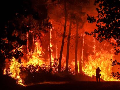 Una persona frente a las llamas en un incendio forestal cerca de Belin-Beliet, suroeste de Francia, durante la madrugada de este jueves.