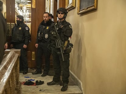 Oficiales de policía del Capitolio resguardan el pasillo donde Ashli Babbit recibió el disparo. En el video, el momento exacto del incidente.