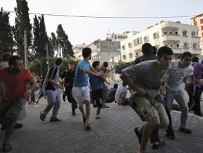 Palestinos se agacham durante bombardeio em Gaza.