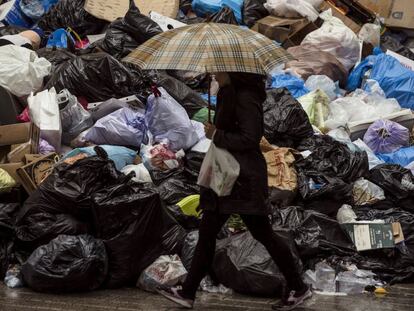 Una mujer camina por una calle de Málaga junto a la basura acumulada.