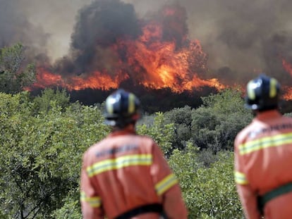 Dos bomberos observan las llamas cerca de Sumacarcer (Valencia).