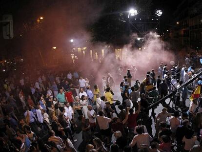 Alborotadores disfrazados de presos lanzan botes de humo en la calle Génova de Madrid mientras habla Mariano Rajoy.
