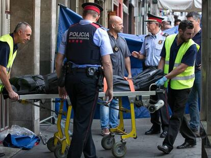 Dos operarios retiran uno de los cuerpos del lugar del crimen.