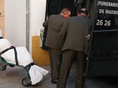 Trabajadores de los servicios funerarios trasladan el cadáver del hombre fallecido como consecuencia de un incendio.