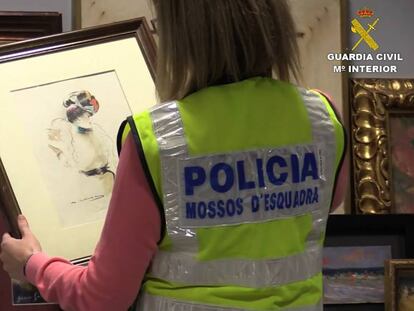 Una policía con uno de los cuadros falsificados.